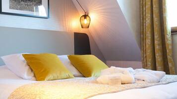 A hotel room with a bed, yellow pillows, a bedside lamp, and a framed picture on the wall.