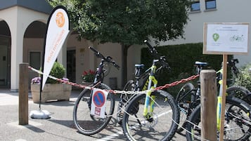 Ett område avsett för cykelparkering med en skylt som visar var laddstationerna för elfordon finns.
