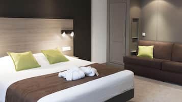 A modern hotel room with a large bed, a brown sofa, and a wardrobe.