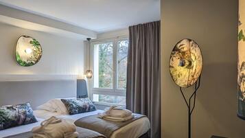 A hotel room with two beds, a desk, and a large window.