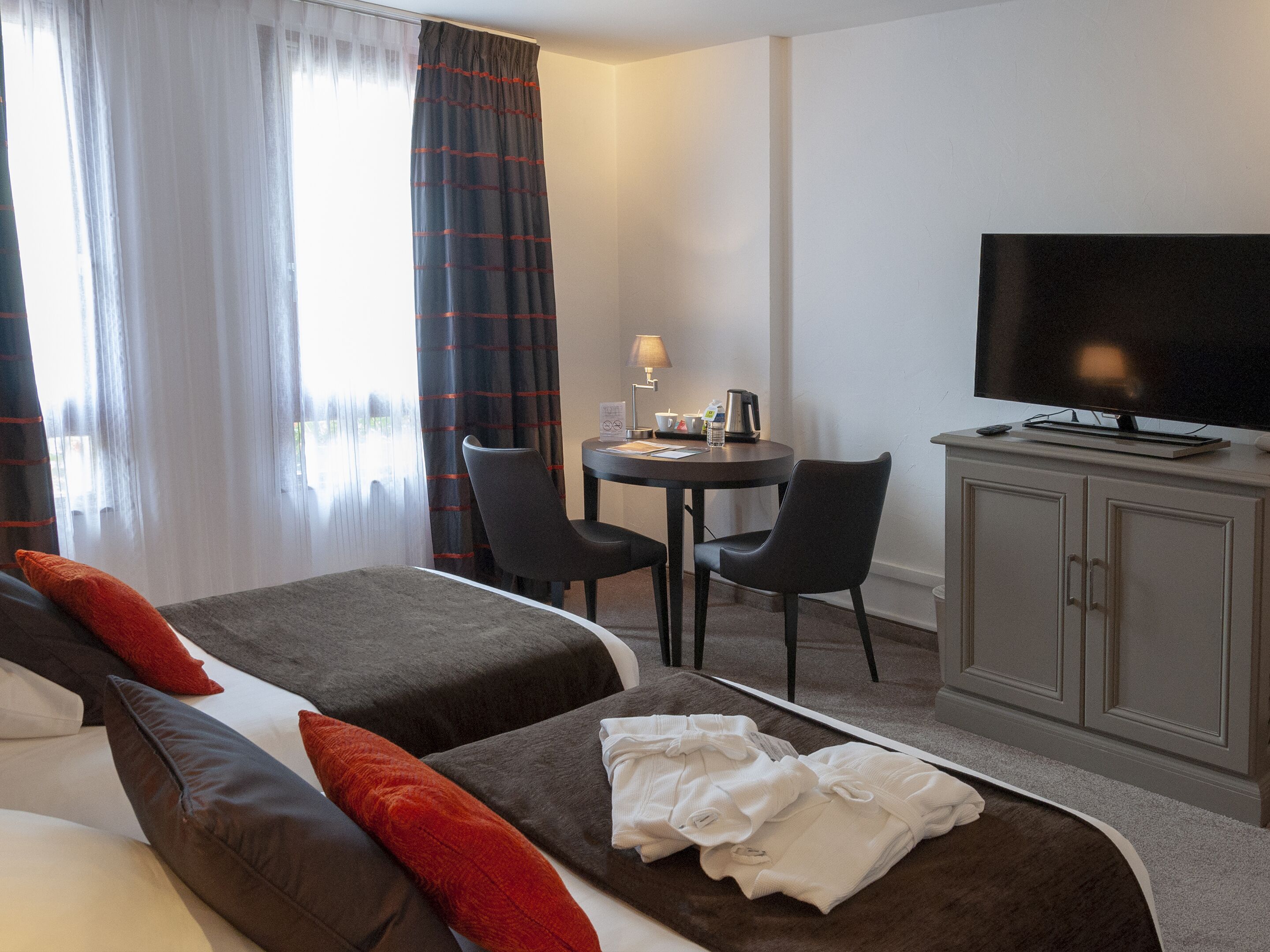 Una habitación de hotel con dos camas, televisión, escritorio con lámpara y armario.