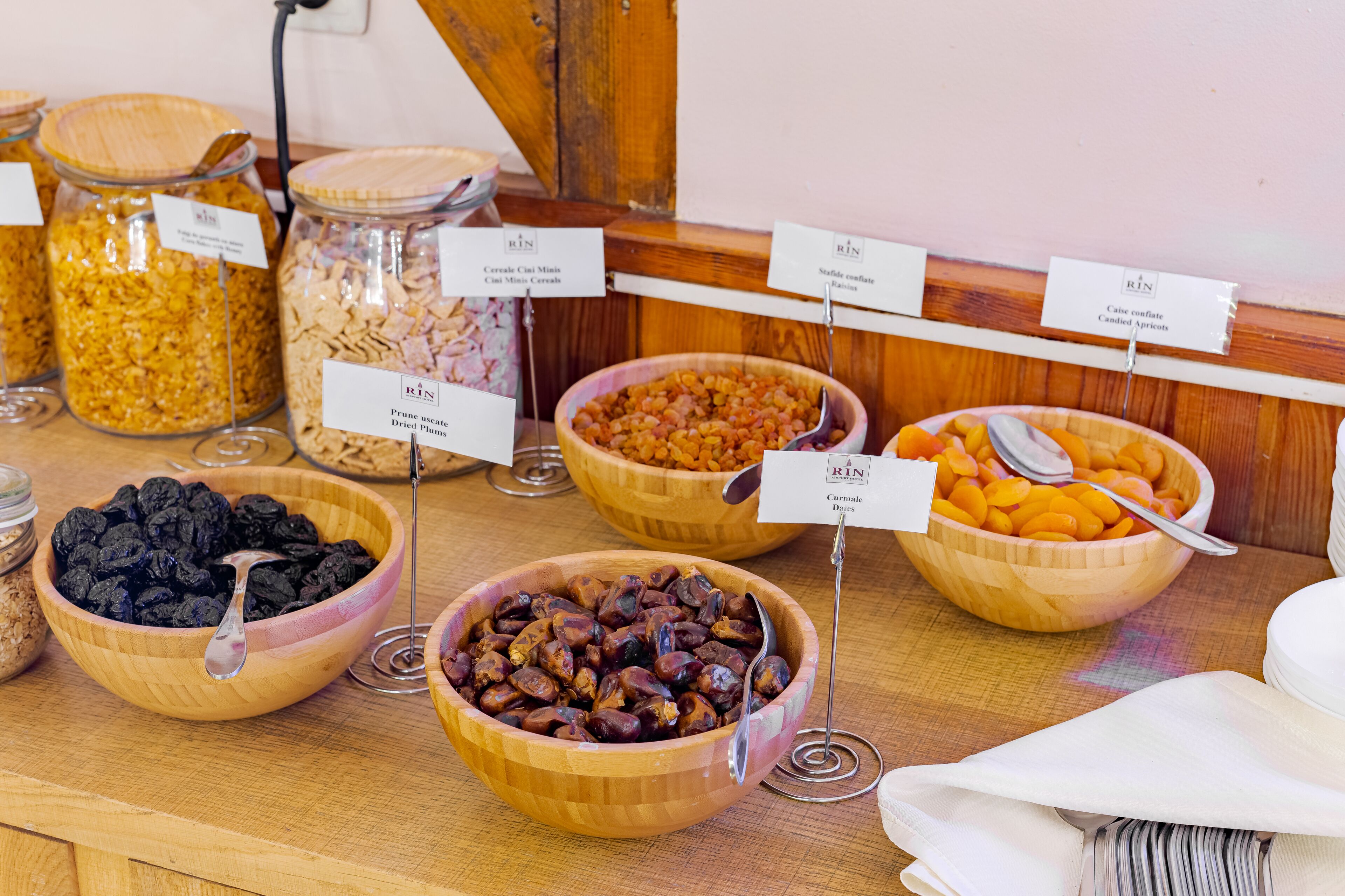 A buffet with various food items in bowls and jars, labeled with their names.