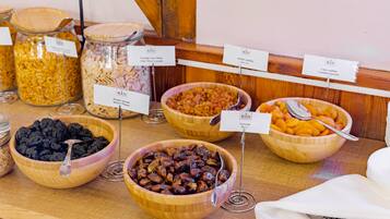 A buffet with various food items in bowls and jars, labeled with their names.