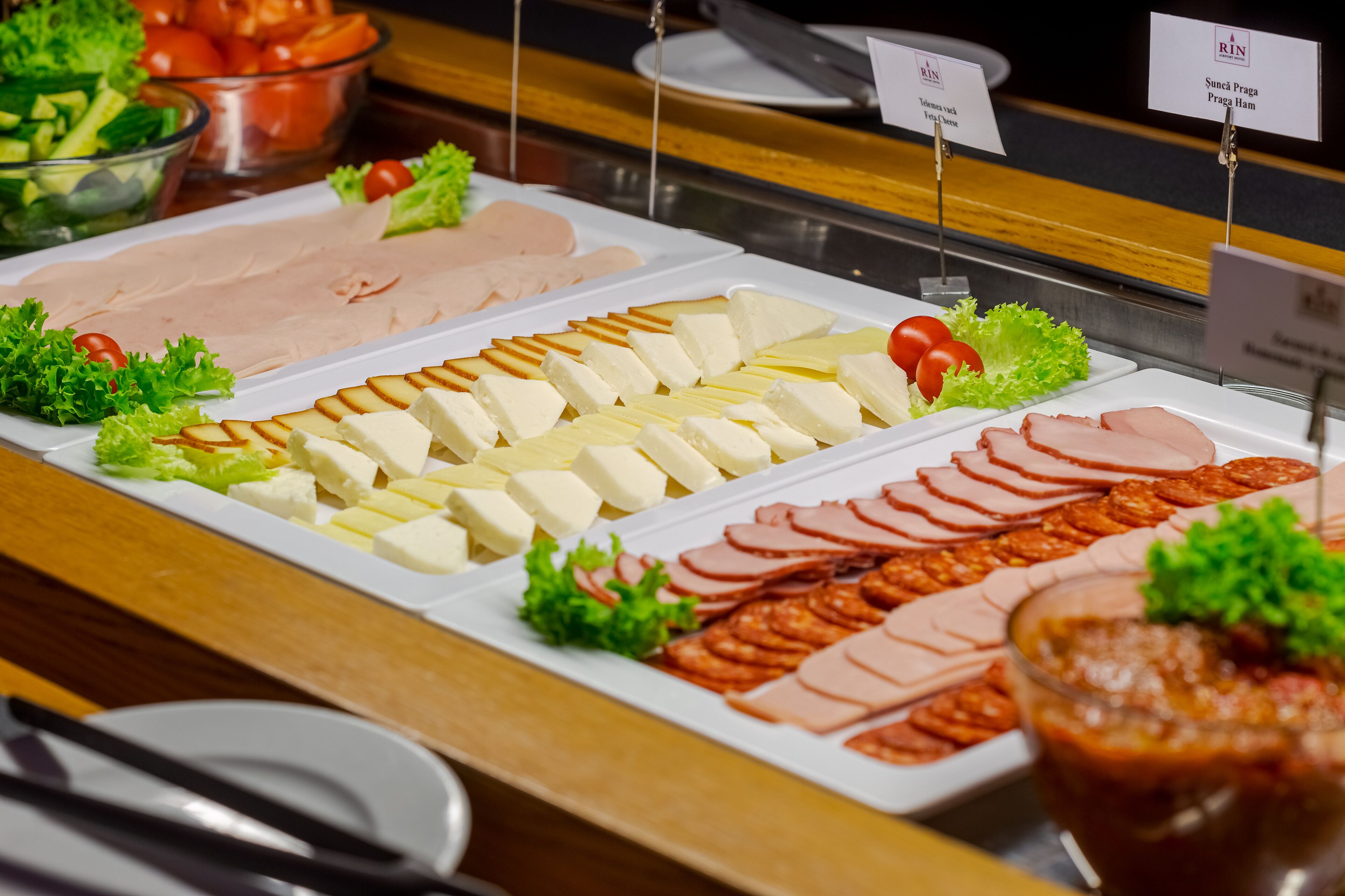 Buffet-pöydässä on tarjolla monenlaista ruokaa, kuten viipaloituja lihatuotteita, juustoja ja kasviksia.