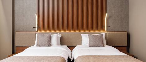 A hotel room with two beds, a wooden headboard, and a textured wall panel.