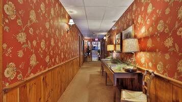 A hallway with floral wallpaper, wooden paneling, a reception desk, and a Christmas tree.