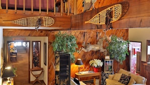 Un interior de madera con una escalera, un comedor y una sala de estar con un sofá y una lámpara.