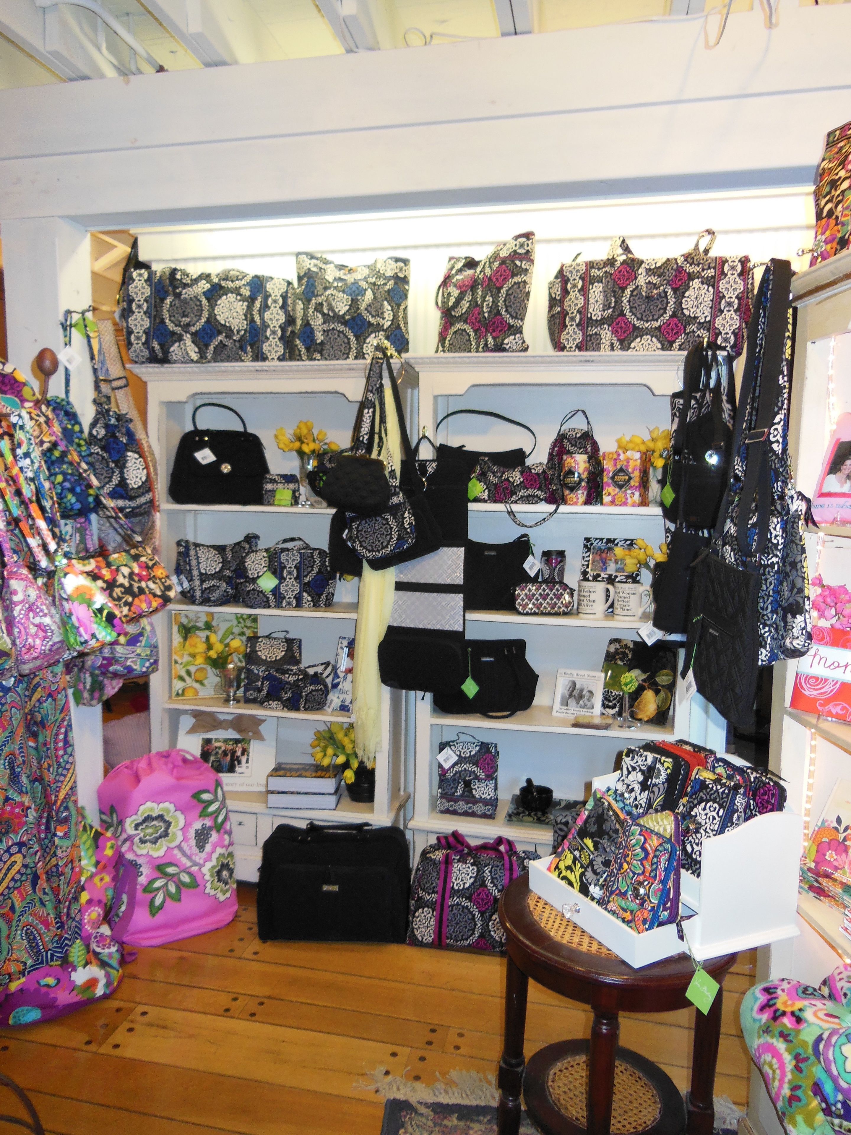 A boutique with shelves of patterned handbags and a mannequin displaying colorful bags.