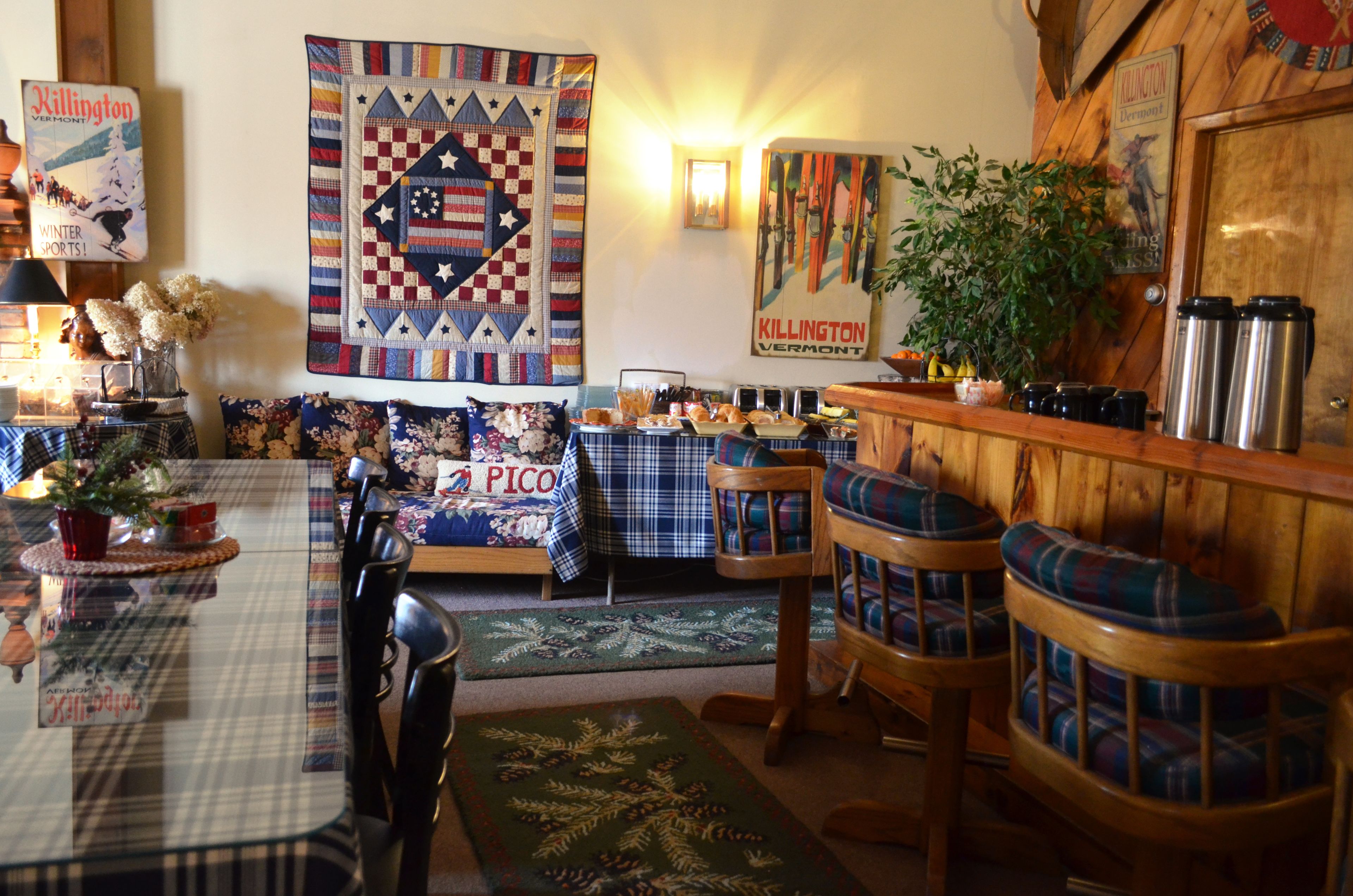 A cozy room with a plaid sofa, a wooden bar area, and a quilt hanging on the wall.