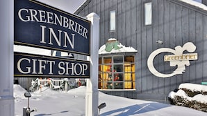 Un cartel anuncia el Greenbrier Inn y una tienda de regalos, con el suelo cubierto de nieve.