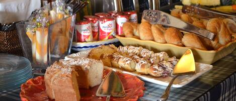 A buffet table with various food items, including pastries, bread, and condiments.