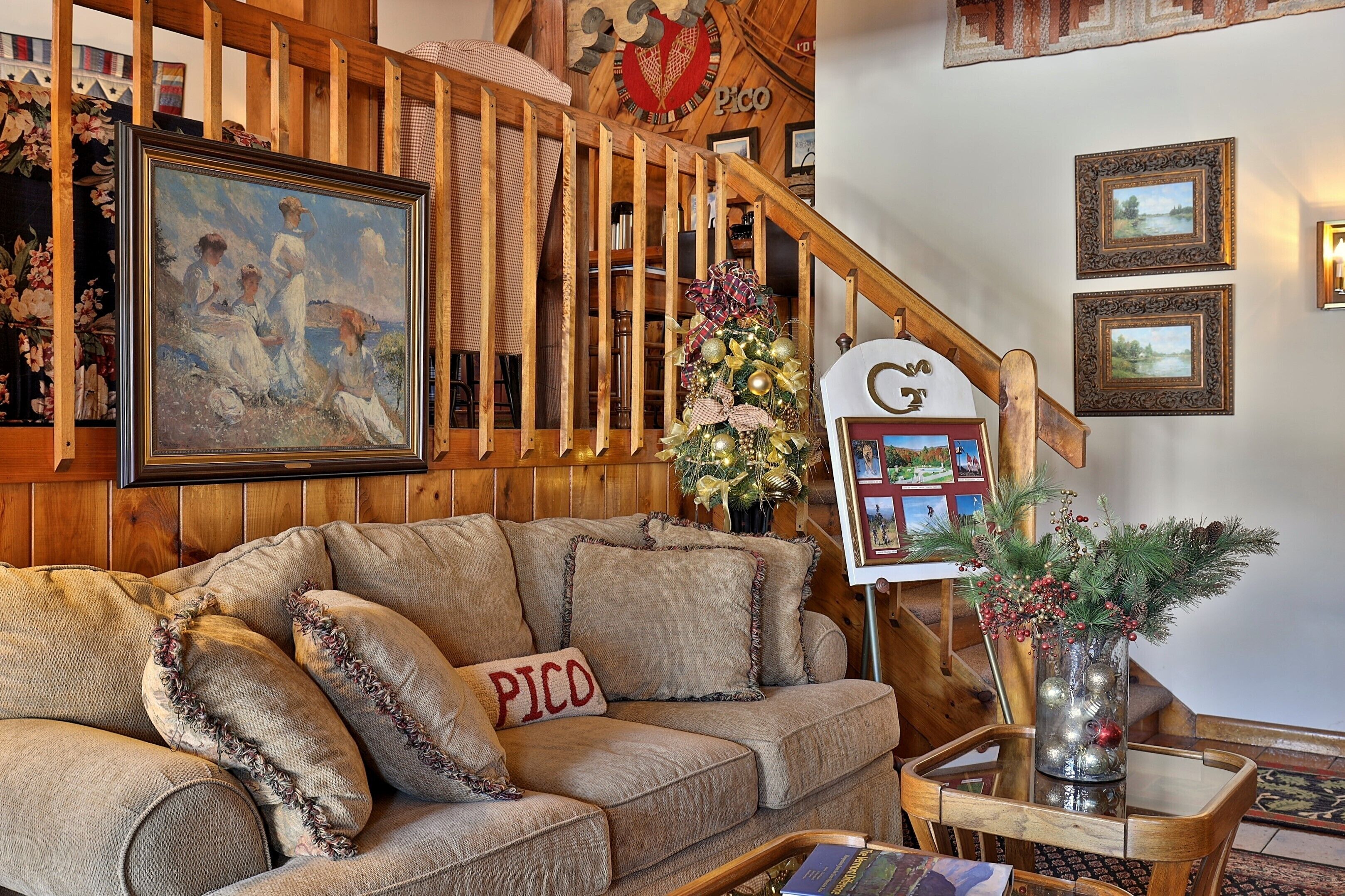 Un salon chaleureux avec un escalier en bois, un tableau et un sapin de Noël.