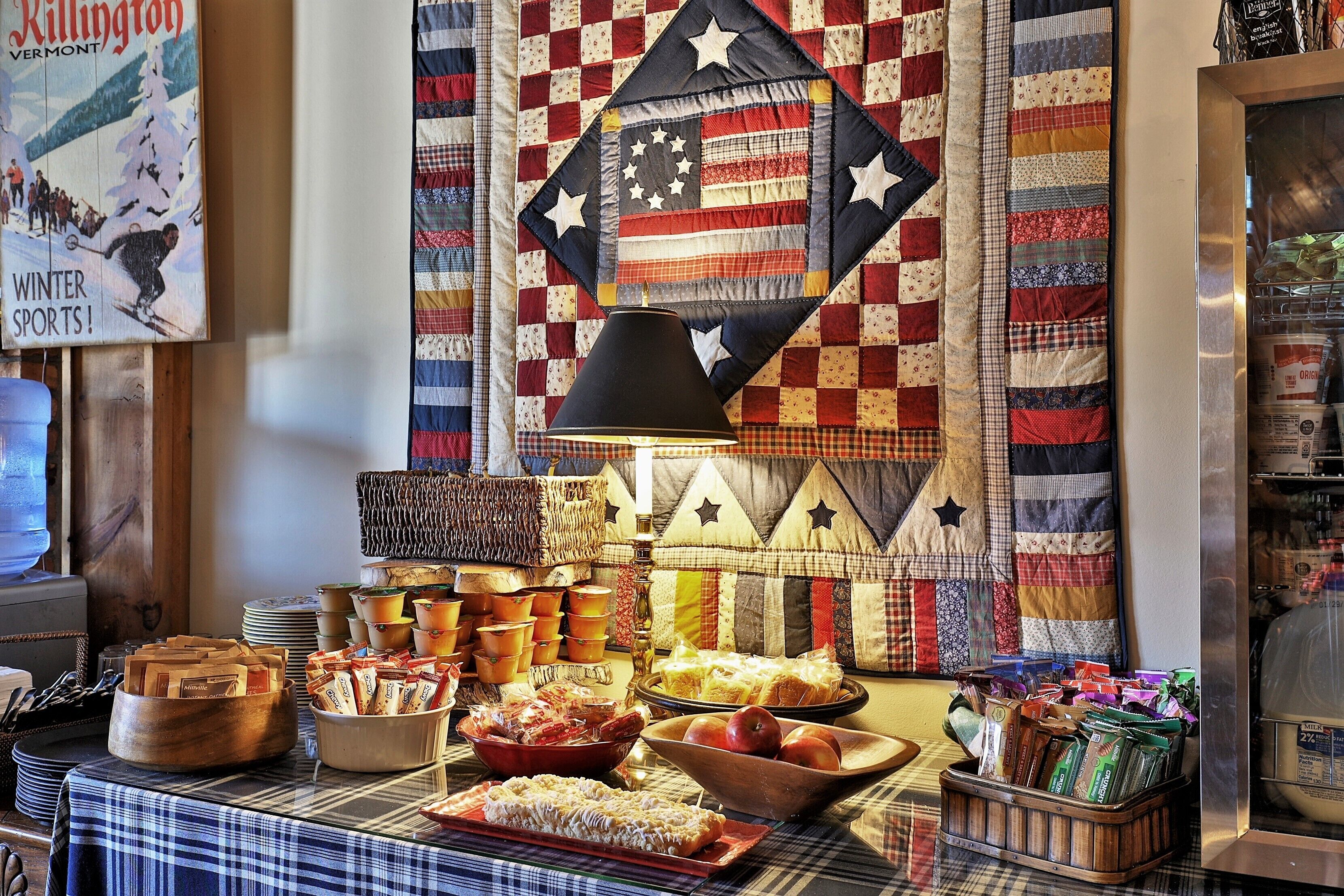 A buffet table with various food items and a quilted wall decoration.