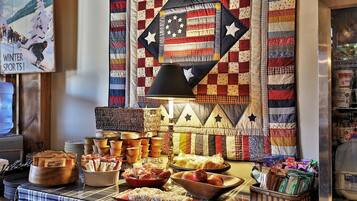 A buffet table with various food items and a quilted wall decoration.