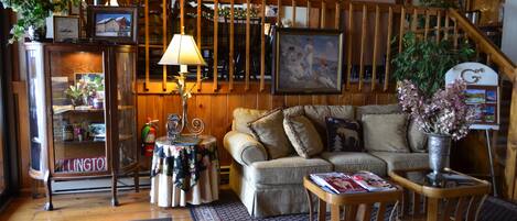 A cozy living room with a wooden staircase, a glass display cabinet, and a comfortable sofa.