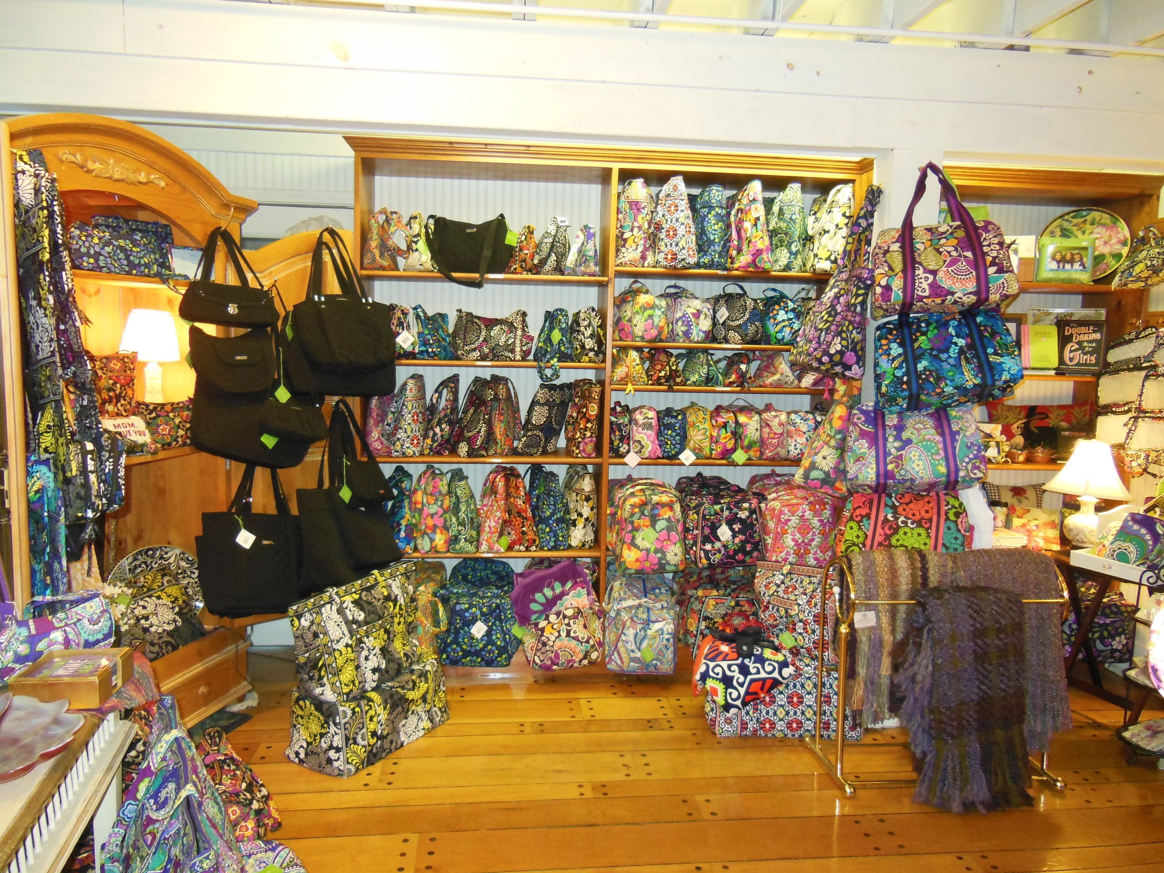 Un magasin où les étagères sont remplies de sacs colorés et où d’autres sacs sont exposés sur le sol.