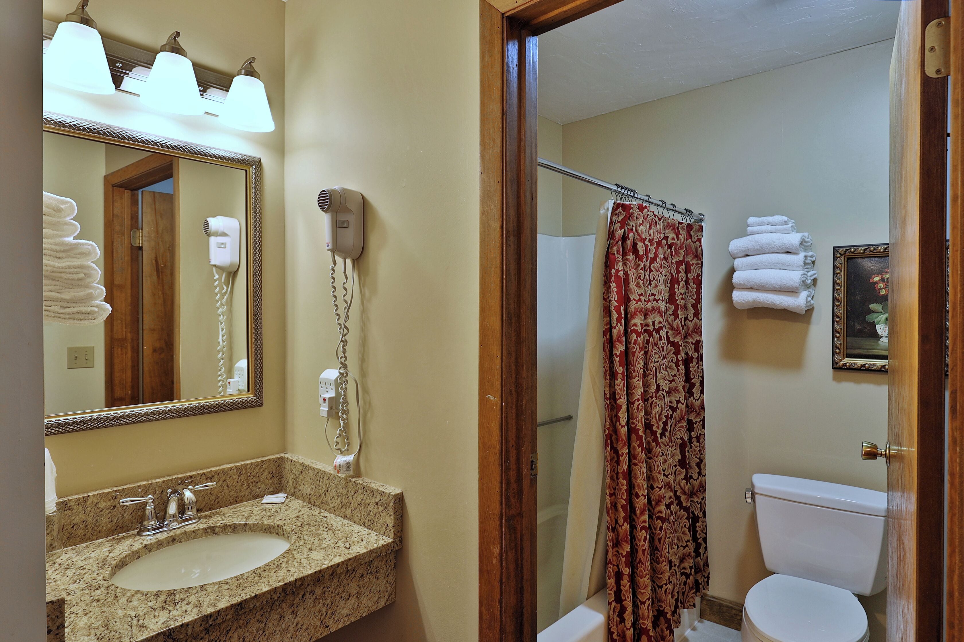 A bathroom with a sink, mirror, hair dryer, and a shower curtain.
