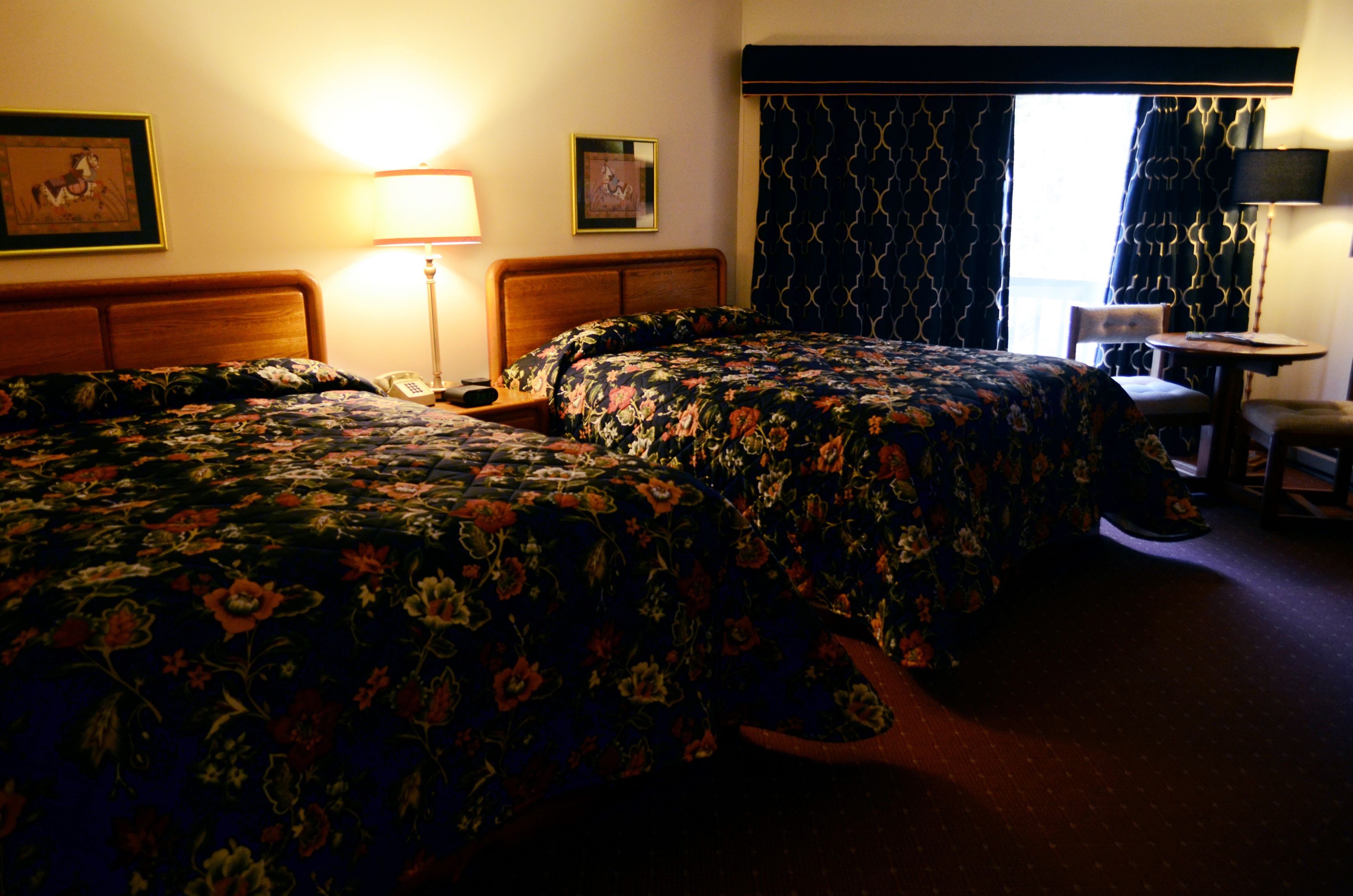 Ein Hotelzimmer mit zwei Betten, einem Schreibtisch und einem Stuhl.
