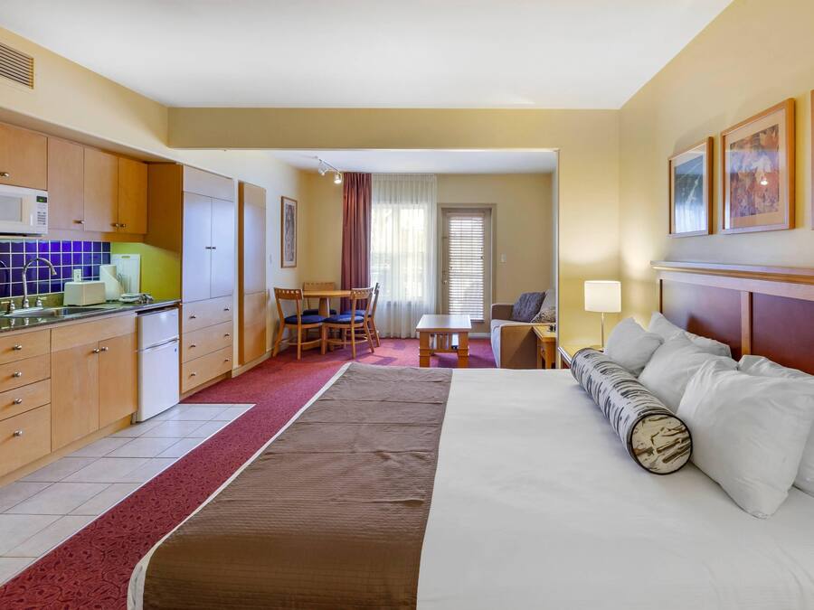 Une chambre d’hôtel équipée d’un lit, d’un bureau, d’une chaise, d’un four à micro-ondes, d’un réfrigérateur et d’une fenêtre avec des rideaux.