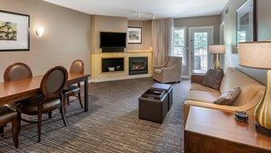 Une chambre d’hôtel équipée d’une table à manger, de chaises, d’un canapé, d’une télévision, d’une cheminée et d’une lampe.