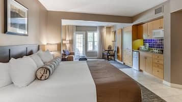 Habitación de hotel con una cama grande, un escritorio, una silla y una kitchenette.