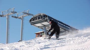 A ski lift with a person snowboarding down the slope.