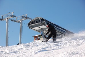 Un télésiège avec une personne qui descend la pente en faisant du snowboard.