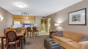 Une chambre d’hôtel moderne avec un coin repas, un canapé et un tableau encadré au mur.