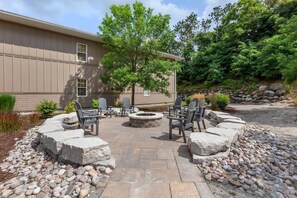 A patio with stone seating and a fire pit, surrounded by a stone wall and greenery. - Carriage Ridge Resort, an Ascend Collection Resort (Oro-Medonte)