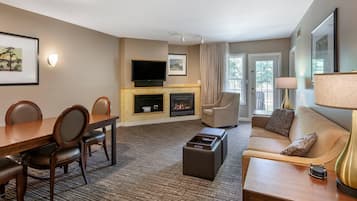 Une chambre d’hôtel équipée d’une table à manger, de chaises, d’un canapé, d’une télévision, d’une cheminée et d’une lampe.