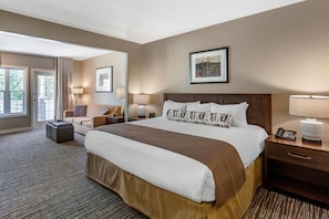 A hotel room with a large bed, a sofa, a desk, and a chair. There are two lamps on the desk and a phone on the bedside table. - Carriage Ridge Resort, an Ascend Collection Resort (Oro-Medonte)