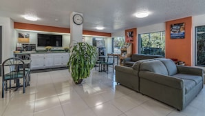 Un moderno vestíbulo de hotel con zona de comedor, un sofá y una planta grande.
