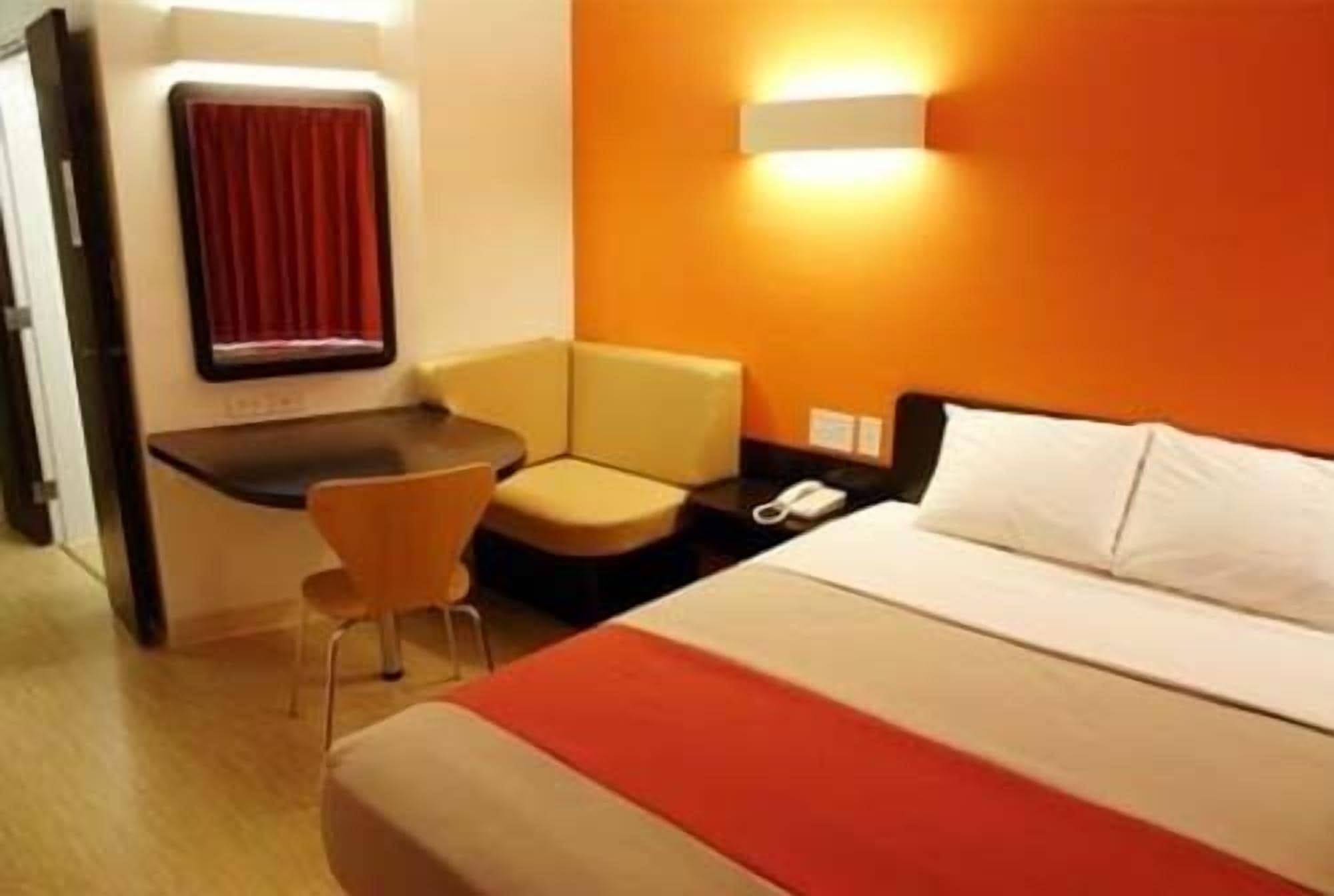A hotel room with a bed, a desk, a chair, and a telephone.