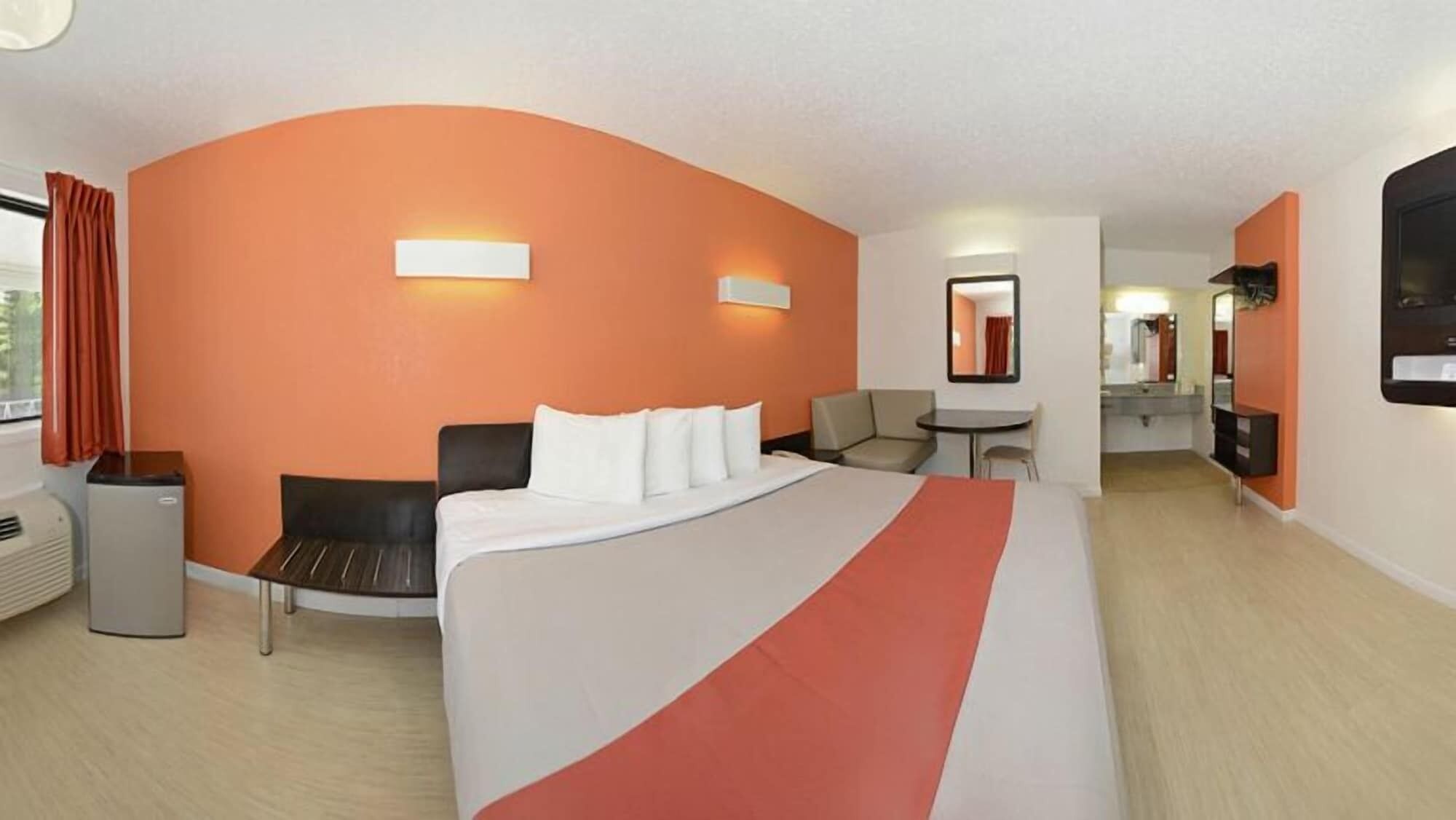 Habitación de hotel con una cama grande, un escritorio, una silla, un sofá, un cesto de basura y un televisor.