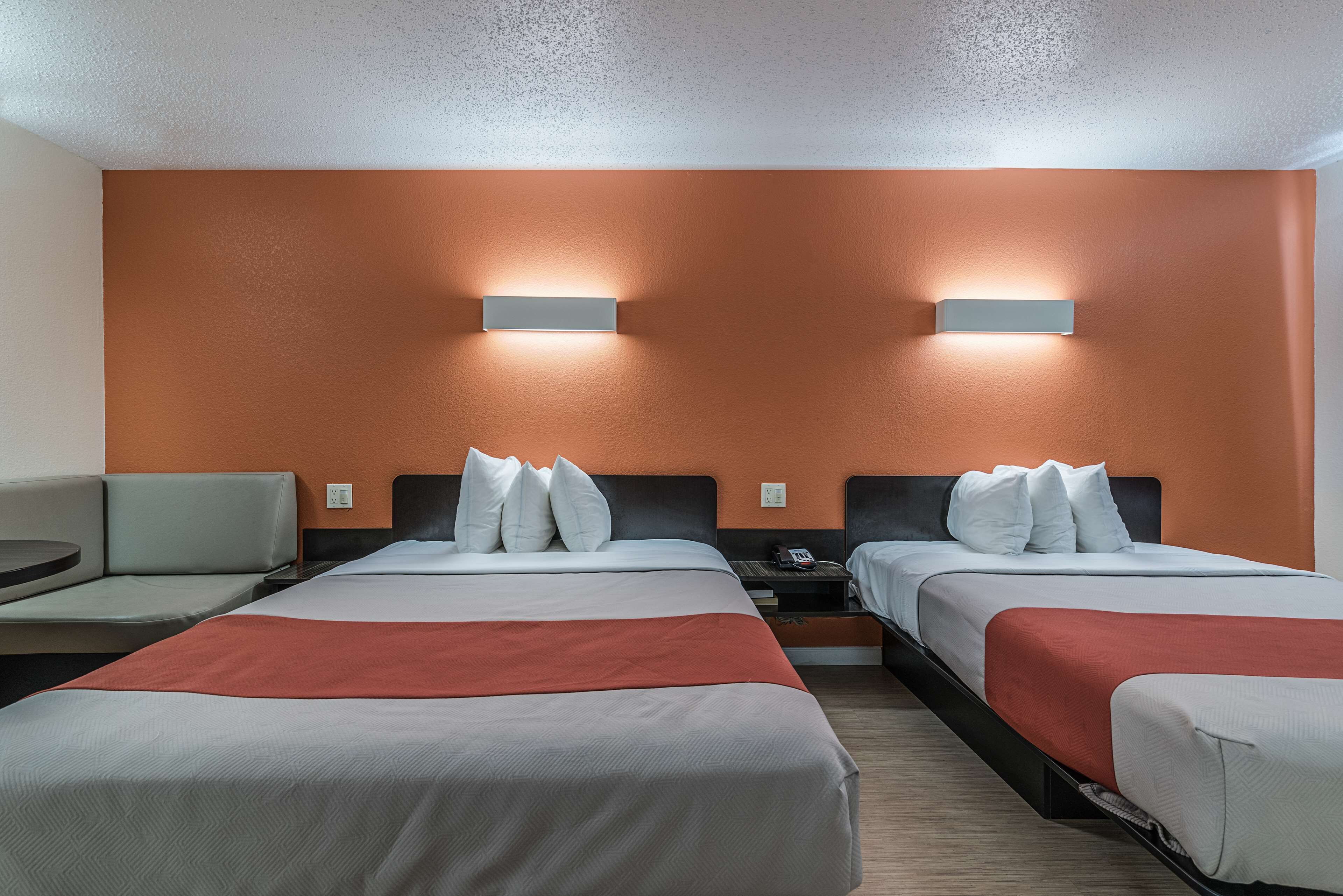 A hotel room with two beds, a sofa, and a small table.