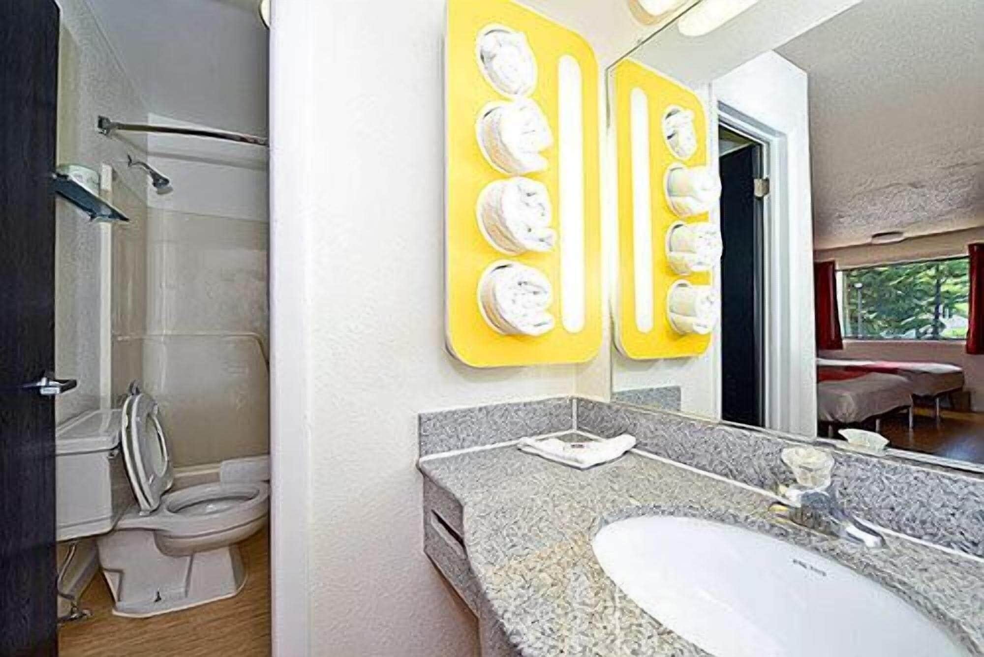 A bathroom with a shower, toilet, and a sink with a mirror.