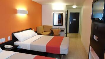 A hotel room with two beds, a desk, a chair, a TV, and a mirror.