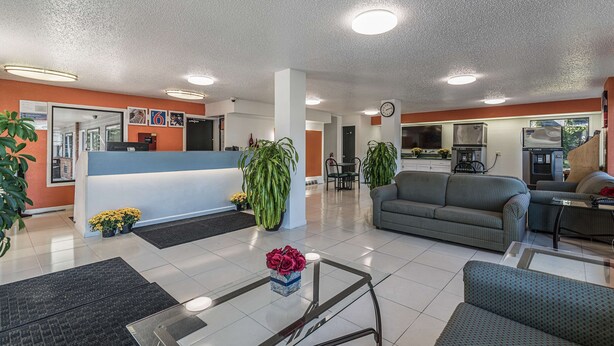 Un vestíbulo de hotel con un mostrador de recepción, zona de estar y cocina al fondo.