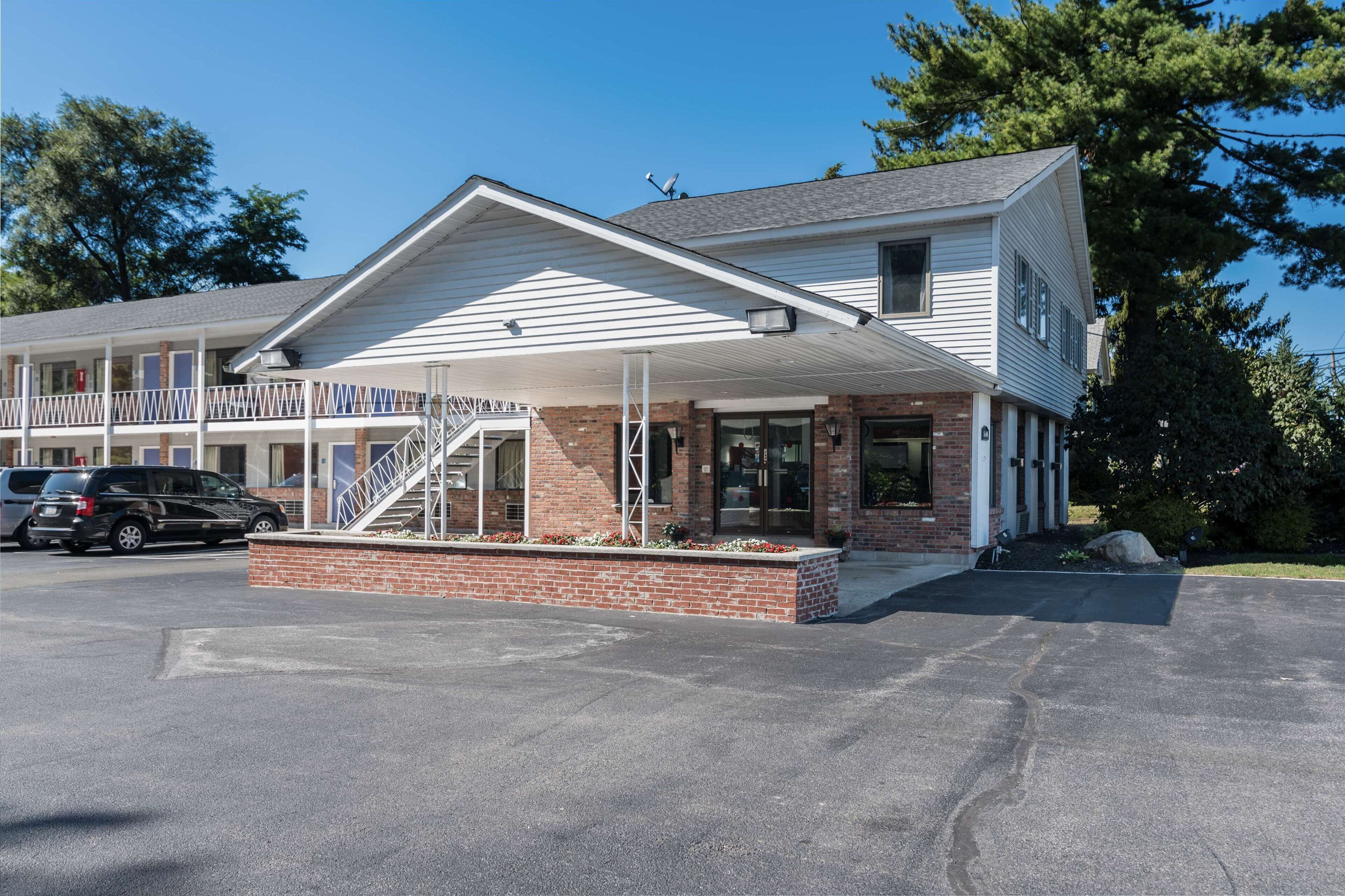 A motel with a covered front porch, brick foundation, and a staircase leading to the entrance.