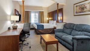 A hotel room with a bed, a desk with a chair, a sofa, a coffee table, and a television. - Citrus Suites Redlands Loma Linda Hotel (Redlands)