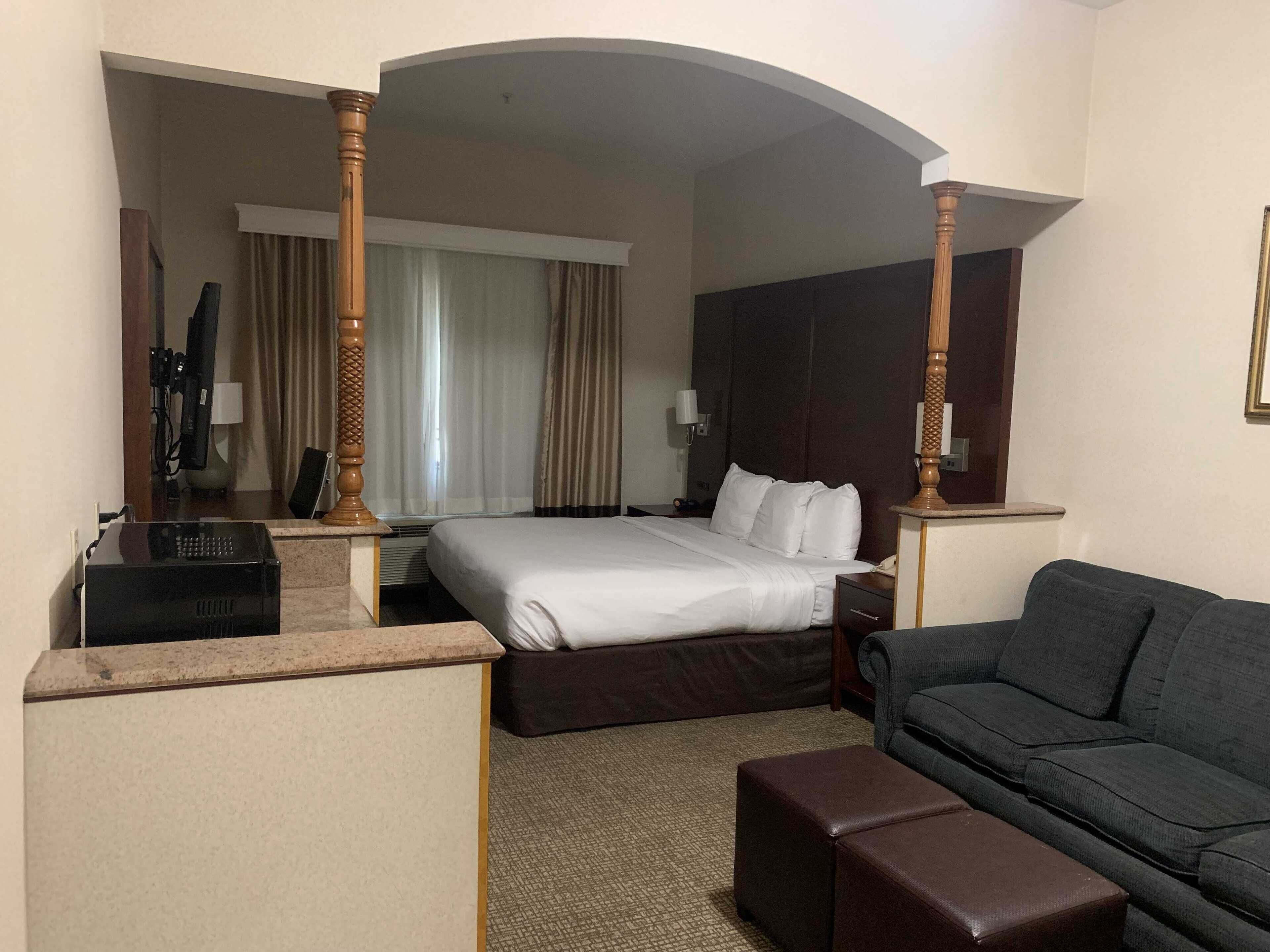 A hotel room with a bed, a desk, a television, and a couch.