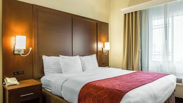 Una habitación de hotel con una cama grande, dos mesitas de noche, un teléfono y lámparas de pared.