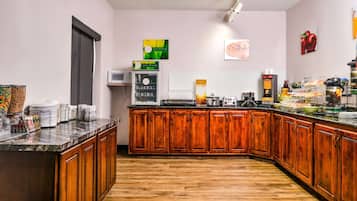 Une cuisine dotée de meubles en bois, d’un plan de travail en marbre, d’un four à micro-ondes et de divers appareils électroménagers.