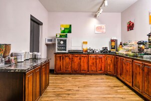 Una cocina con armarios de madera, encimera de mármol, microondas y diversos electrodomésticos.