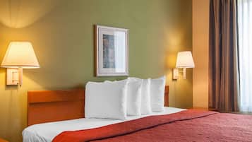 Ein Hotelzimmer mit einem Bett, zwei Wandlampen, einem gerahmten Bild und einem Fenster mit Vorhängen.
