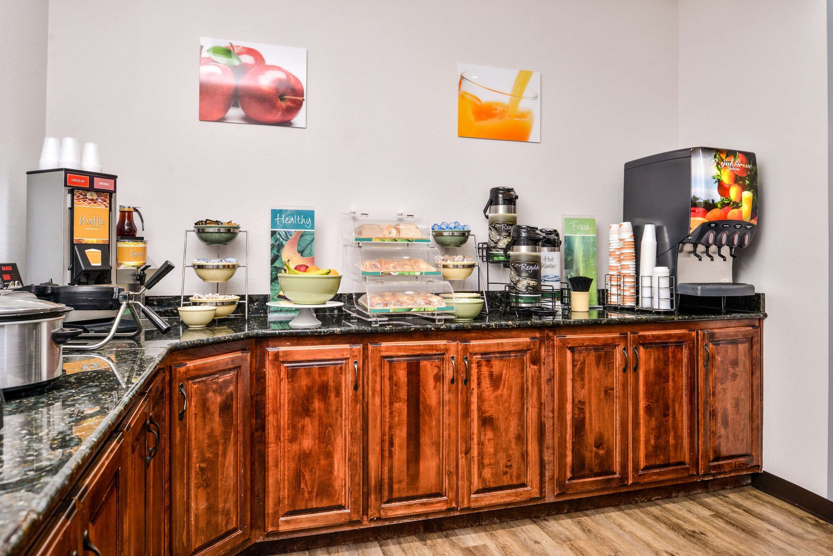 Un comptoir-buffet pour le petit-déjeuner, avec des machines à café, des distributeurs de jus de fruits et divers aliments.