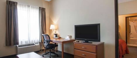 Une chambre d’hôtel équipée d’un bureau, d’une chaise, d’une télévision et d’une armoire.