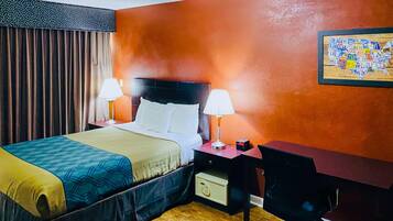 Una habitación de hotel con una cama, dos lámparas de noche, un escritorio con una silla y un reloj de pared.