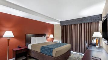 Habitación de hotel con cama, dos lámparas de noche, mesita de noche, televisor y escritorio con lámpara.