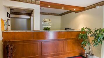 A reception desk with a wooden finish, a logo for EconoLodge Inn & Suites, and a potted plant to the right.